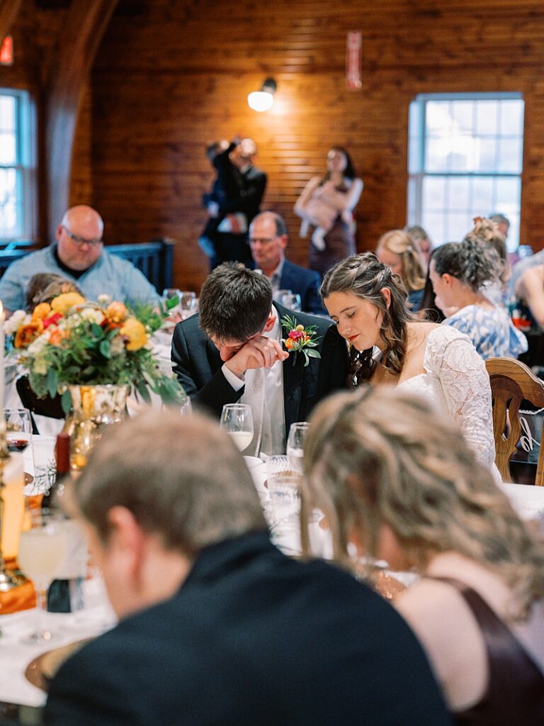 Bride and groom praying during dinner at wedding reception
